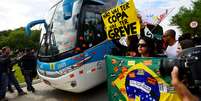 O ônibus com os atletas foi cercado pelos manifestantes, que colavam faixas pedindo o famoso bordão "da Copa eu abro mão, eu quero mais dinheiro para a saúde e educação"  Foto: Daniel Ramalho / Terra