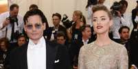 Ao lado do namorado Johnny Deep, no Festival de Cannes 2014, Amber Heard brilha com batom vermelho-escuro e brilho nos olhos, como do vestido   Foto: Getty Images