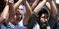 <p>Palestinos amarram as m&atilde;os e&nbsp;gritam slogans durante uma manifesta&ccedil;&atilde;o de solidariedade aos prisioneiros palestinos detidos sem julgamento&nbsp;em pris&otilde;es israelenses, na cidade de Nablus, na Cisjord&acirc;nia, em 26 de maio</p>  Foto: Reuters