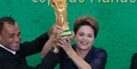 <p>Ao lado de Cafu, Dilma ergueu a taça em gesto tradicional do capitão da Copa do Mundo antes do início do Mundial</p>  Foto: EFE