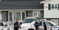 <p>Oficiais se escondem atrás de viatura em Moncton, New Brunswick, Canada, em 4 de junho</p>  Foto: Reuters