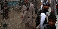 <p>Pessoas observam uma janela lateral de um &ocirc;nibus. que foi danificado por explos&otilde;es, em Cabul</p>  Foto: Reuters