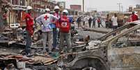 <p>Equipe da Cruz Vermelha trabalha em local onde carros-bomba explodiram em Jos, na Nigéria, em 21 de maio</p>  Foto: AP