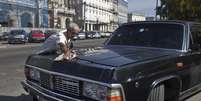 Limusines que serviram a Fidel Castro foram transformadas em táxis em Havana, capital de Cuba. Na imagem, motorista Moises Suarez limpa um modelo soviético que já pertenceu ao ditador cubano  Foto: Franklin Reyes / AP