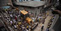 <p>Equipes de resgate retiram o corpo de uma vítima entre os escombros de um edifício que desabou em Nova Deli, Índia, em 28 junho</p>  Foto: AP