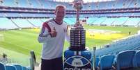 Podolski na Arena Grêmio ao lado de troféu da Copa Libertadores  Foto: Twitter / Reprodução
