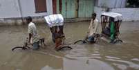 <p>Pessoas caminham em uma rua inundada após pesadas chuvas em Agartala, capital do estado de Tripura, nordeste da Índia, em 11 de junho. A região é afetada por um surto de Malária</p>  Foto: Jayanta Dey / Reuters