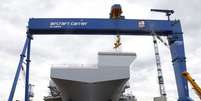 <p>Trabalhadores caminham em frente ao "HMS Queen Elizabeth", o primeiro de dois porta-aviões construídos pela empresa britânica de defesa BAE Systems, no Rosyth Dockyard em Fife, Escócia, em 17 de junho</p>  Foto: Russell Cheyne / Reuters