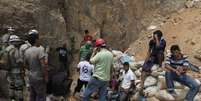 <p>Mineiros e equipes de resgate se concentram na entrada de uma mina de ouro bloqueada por um deslizamento de terra em San Juan Arriba, periferia de Tegucigalpa, em 03 de julho</p>  Foto: Jorge Cabrera / Reuters