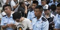 <p>Manifestantes s&atilde;o levados&nbsp;por policiais depois de passarem uma noite detidos no distrito financeiro central de Hong Kong, em&nbsp;2 de julho</p>  Foto: Tyrone Siu / Reuters