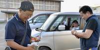 Moradores de Sendai ouvem pelo rádio as últimas informações sobre a chegada de um pequeno tsunami, que não causou danos significativos  Foto: Kyodo / Reuters