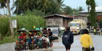 <p>Moradores cruzam&nbsp;uma estrada inundada em Mindanao, nas Filipinas, em&nbsp;15 de julho</p>  Foto: Jeoffrey Maitem / Getty Images 