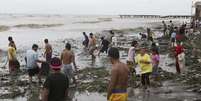 <p>Moradores à beira-mar após a passagem do tufão Rammasun, no litoral da cidade de Rosário, ao sul de Manila</p>  Foto: Erik De Castro / Reuters