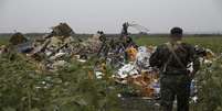 <p>Separatista ucraniano observa um dos vários campos de destroços do voo MH17</p>  Foto: Maxim Zmeyev (UKRAINE - Tags: POLITICS TRANSPORT DISASTER CIVIL UNREST) / Reuters