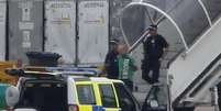 <p>Um homem é escoltado pela polícia para fora do avião da Qatar Airways, no aeroporto de Manchester, norte da Inglaterra, nesta terça-feira, 5 de agosto</p>  Foto: Andrew Yates / Reuters