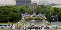 Pessoas enfrentam a chuva para orar pelas vítimas do ataque atômico  Foto: Kyodo / Reuters
