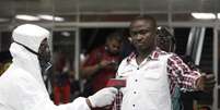Funcionário do aeroporto de Lagos, na Nigéria, confere condições de passageiro  Foto: AP
