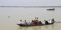 Pessoas transportam pertences em pequeno barco em meio às inundações no norte da Índia  Foto: Stringer  / Reuters