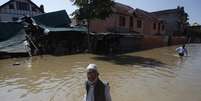 Cidadãos da Caxemira caminham em meio a água e casas danificadas, em uma rua inundada, em Srinagar , em 14 de setembro  Foto: Danish Ismail / Reuters