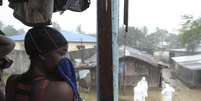 Mulher observa trabalhadores de saúde com roupas especiais em mercado de Monróvia. 17/08/2014  Foto: 2Tango / Reuters