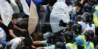 <p>Manifestantes com guarda-chuvas bloqueiam rua perto da sede do governo de Hong Kong</p>  Foto: Carlos Barria / Reuters