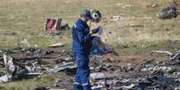 <p>Membro do Minist&eacute;rio da Emerg&ecirc;ncia busca por pertences de passageiros mortos no local em que caiu o voo MH17</p>  Foto: Shamil Zhumatov / Reuters