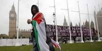 <p>Um homem coberto por&nbsp;uma bandeira palestina caminha pr&oacute;ximo ao Parlamento em Londres, em 13 de outubro</p><p>&nbsp;</p>  Foto: Luke MacGregor / Reuters