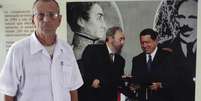 Um dos médicos cubanos tira foto ao lado de painel de líderes latinos  Foto: Enrique De La Osa / Reuters