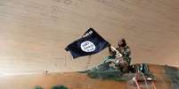 <p>Combatente do Estado Islâmico ergue uma bandeira da organização terrorista em cima de um caça, em agosto deste ano</p><p> </p>  Foto: AP