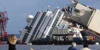 Pessoas olham navio de cruzeiro Costa Concordia tombado na costa da Toscana, na Itália  Foto: Tony Gentile / Reuters