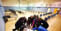 <p>Chefe de seção eleitoral Deloris Reid-Smith lê juramento junto a trabalhadores antes de abertura das urnas em igreja de Charlotte</p>  Foto: Chris Keane / Reuters