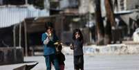 Crianças sírias comem milho em uma rua em Douma, no leste da al-Ghouta, perto de Damasco; o EI fechou escolas ao leste do país nesta sexta  Foto: Bassam Khabieh  / Reuters