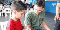 O professor Caio Ferraro observa aluno treinando a montagem do cubo  Foto: Giovani de Oliveira / Divulgação