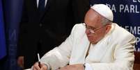 <p>Papa Francisco assina livro em cerim&ocirc;nia no Parlamento Europeu em Estrasburgo, na ter&ccedil;a-feira.</p>  Foto: Christophe Karaba / Reuters