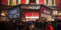 Manifestantes ergue cartazes de protesto em frente a uma loja da rede Macy's, em Nova York. 27/11/2014.  Foto: Andrew Kelly / Reuters