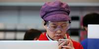 Mulher chinesa observa iPhone 6 após lançamento   Foto: Feng Li / Getty Images 