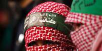 <p>Palestina mascarada assiste a apresentação de membros das brigadas al-Qassam, braço armado do movimento Hamas, em Gaza</p>  Foto: Mohammed Salem / Reuters