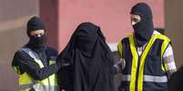 Policiais mascarados espanhóis prendem uma mulher suspeita de participar de uma organização que recrutava mulheres para os jihadistas do Estado Islâmico  Foto: Jesus Blasco de Avellaneda / Reuters