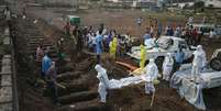 <p>Profissionais de saúde enterram corpo de vítima de Ebola em Freetown, Serra Leoa</p>  Foto: Baz Ratner / Reuters