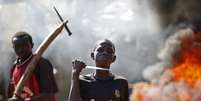 <p>Garoto exibe faca em frente a uma barricada em chamas durante protesto, depois que tropas francesas abriram fogo contra manifestantes que bloqueavam uma estrada em Bambari, na República Centro-Africana, em maio</p><p> </p>  Foto: Goran Tomasevic / Reuters