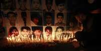 <p>Um homem coloca uma rosa na&nbsp;frente de retratos das v&iacute;timas do ataque talib&atilde; na Escola P&uacute;blica do Ex&eacute;rcito em Peshawar, durante uma vig&iacute;lia &agrave; luz de velas, em Lahore&nbsp;</p>  Foto: Mohsin Raza / Reuters