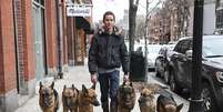 <p>Augusto de Oliveira caminha pelas ruas das cidades de Massachusetts com seus cães</p>  Foto: Daily Mail / Reprodução