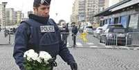 Policial deposita flores em supermercado atacado por extremista (foto: Reuters)  Foto: BBC Mundo / Copyright