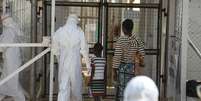 Agente da saúde acompanha novos pacientes de Ebola num centro de tratamento nos arredores de Freetown, em Serra Leoa, em dezembro. 22/12/2014  Foto: Baz Ratner / Reuters