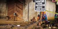<p>Menina &eacute; fotografada em 22 de outubro de 2014 perto de uma placa de sinaliza&ccedil;&atilde;o colocada em&nbsp;uma casa em quarentena,&nbsp;em Port Loko, Serra Leoa</p>  Foto: Michael Duff / AP