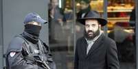 Um policial conversa com um judeu fora do mercado judaico onde quatro ref&eacute;ns foram assassinadas pelo sequestrador Amedy Coulibaly, durante atentado terrorista cometido em Paris  Foto: Francois Mori / AP