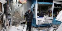 <p>Homem passa por loja danificada por recente ataque em mercado de Donetsk</p>  Foto: Alexander Ermochenko / Reuters