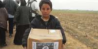 Criança segura um pacote de comida do Programa Mundial de Alimentos da ONU com a logomarca do Estado Islâmico  Foto: Twitter