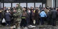 Soldado monta guarda enquanto ajuda humanitária é distribuída aos residentes da cidade de Debaltseve, Ucrânia, em 6 de fevereiro  Foto: Petr David Josek / AP