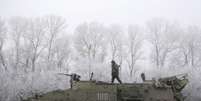 Soldado ucraniano anda em cima de seu veículo blindado na estrada entre as cidades de Dabeltseve e Artemivsk, na Ucrânia, em 15 de fevereiro  Foto: Petr David Josek / AP